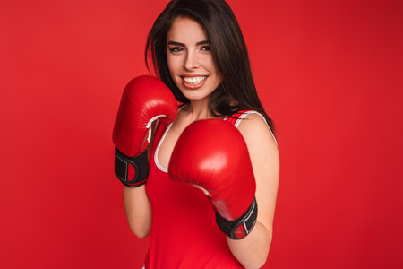Confident Woman in Red Boxing Gloves Posing Against a Vibrant Backgroundの写真素材