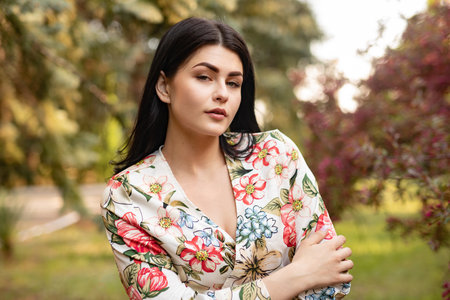 Elegant Woman Posing Outdoors in a Vibrant Flower Pattern Dressの写真素材