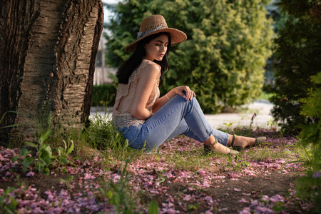 Young Woman Relaxing Outdoors Surrounded by Spring Blossoms and Natureの写真素材