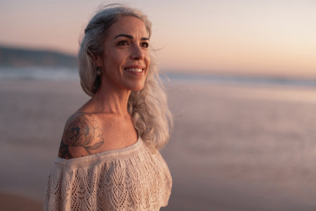 Mature Woman Enjoying A Peaceful Beach Sunset With A Happy Smileの写真素材