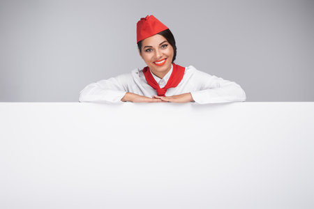 Smiling Flight Attendant Holding a Blank White Banner in a Professional Settingの写真素材