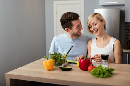 Couple Preparing a Fresh Salad Together in a Modern Home Kitchenの写真素材