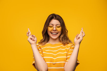 Cheerful Woman in Yellow Outfit Expressing Positivity and Excitement on Studio Backgroundの写真素材