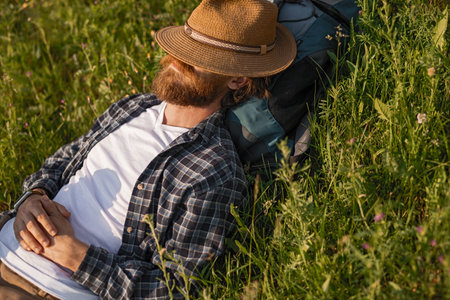 Peaceful Man Relaxing Outdoors in Nature While Lying in Grassy Fieldの写真素材