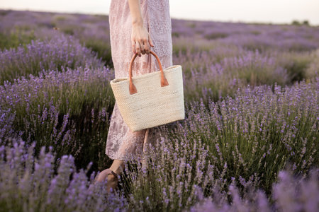 Rustic Woven Bag Held Among Lavender Flowers in Bloom During Sunsetの写真素材
