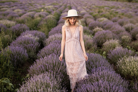 Woman in Lavender Field Wearing Elegant Lace Dress and Wide-Brimmed Hatの写真素材