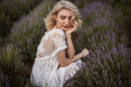 Woman Sitting in Lavender Field Wearing a Lace White Dressの写真素材