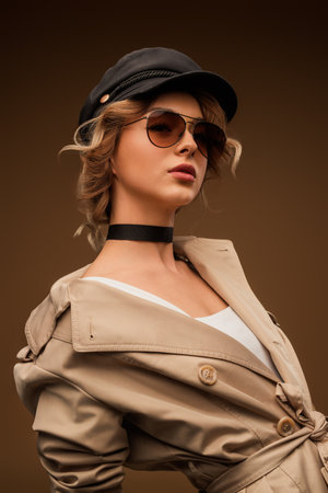 Fashion Forward Woman in Beige Coat Wearing Sunglasses and Capの写真素材