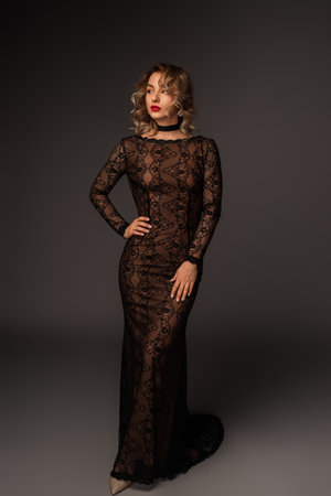 Elegant Woman in a Stylish Black Lace Evening Gown on Grey Backgroundの写真素材