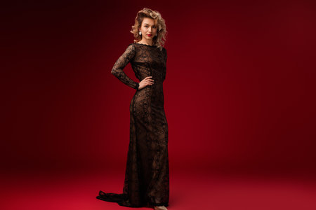 Elegant Woman in Black Lace Evening Gown on Red Backgroundの写真素材