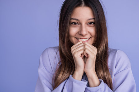 Smiling Woman in Casual Attire Expressing Joy Against a Purple Backgroundの写真素材