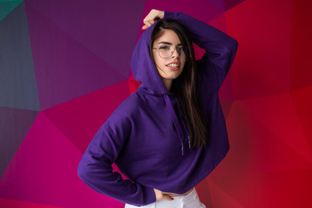 Stylish Woman in Purple Hoodie Posing Against Vibrant Geometric Backgroundの写真素材