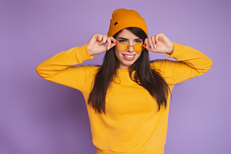 Stylish Young Woman in Vibrant Yellow Attire With Sunglasses and Beanieの写真素材