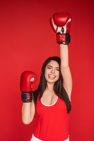 Excited Female Boxer Celebrating Victory in Boxing Gloves on Vibrant Red Background