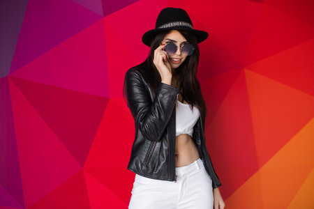 Fashionable Woman Posing in Stylish Outfit Against a Vibrant Colorful Backgroundの写真素材