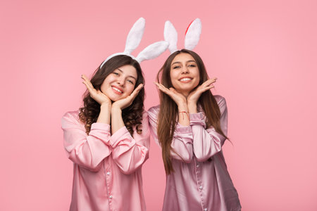 Two Happy Women Posing in Pajamas with Bunny Ears Headbandsの写真素材