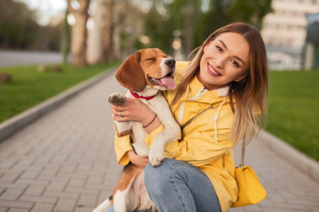 Woman Smiling Outdoors Holding Her Beagle Dog in a Parkの写真素材
