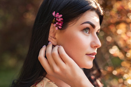 Young Woman with Flowers in Hair Enjoying a Sunny Outdoor Atmosphereの写真素材