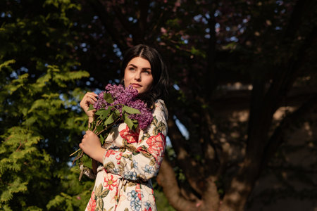 Woman Holding Purple Flowers in Nature During Golden Hourの写真素材