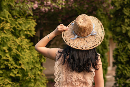 Woman Wearing Stylish Lace Top and Straw Hat in Garden Settingの写真素材