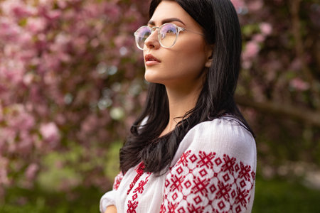 Serene Woman in Traditional Embroidered Attire Among Blooming Cherry Blossomsの写真素材