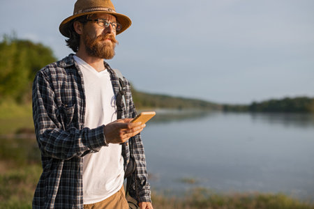 Man With Smartphone Exploring Along Lakeside During Sunset Outingの写真素材