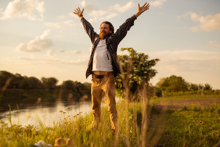 Man Celebrating Freedom in Nature During a Sunny Day Outdoorsの写真素材