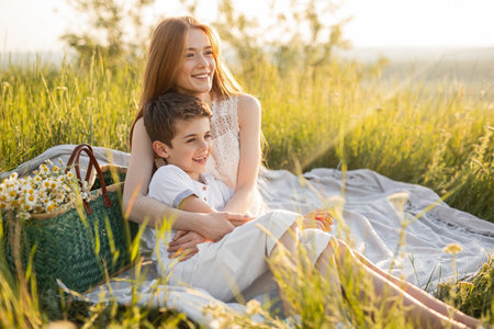 Happy Mother and Son Enjoying a Picnic in a Summer Meadowの写真素材