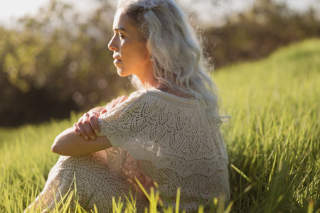 Serene Woman Enjoying Peaceful Moment in Sunlit Fieldの写真素材