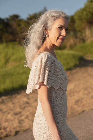 Elegant Woman Strolling Outdoors in a Knitted Dress in Bright Sunlightの写真素材