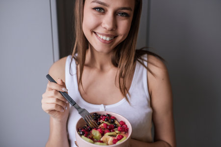 Smiling Woman Enjoying a Healthy Fruit Salad in a Relaxed Settingの写真素材