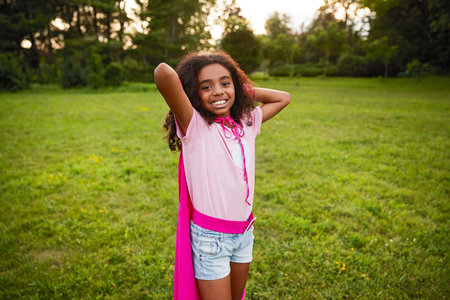 Happy Girl Wearing a Pink Cape Posing in a Summer Parkの写真素材