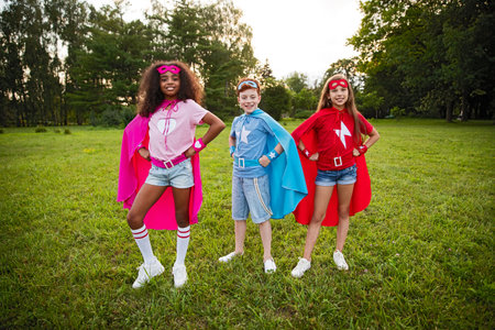 Three Kids Dressed as Superheroes Enjoying Outdoor Fun and Imaginationの写真素材
