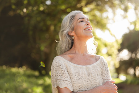 Joyful Woman Enjoying Peaceful Moment in Nature with Sunlightの写真素材
