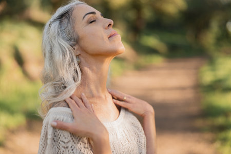 Serene Woman Enjoying Nature Walk in Sunlit Forest Settingの写真素材