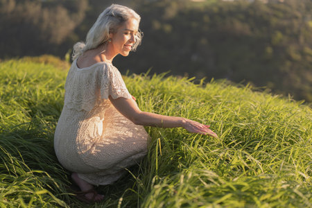 Woman in Summer Dress Enjoying Nature in a Field of Green Grassの写真素材