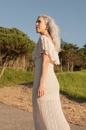 Elegant Woman With Gray Hair Walking Outdoors Amidst Greeneryの写真素材