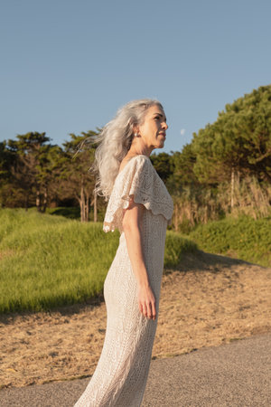 Elegant Woman in Lace Dress Enjoying Outdoor Stroll on a Sunny Dayの写真素材