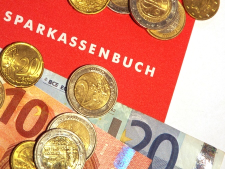 Passbook.  Some Euro notes and coins lying on a German deposits book.の写真素材
