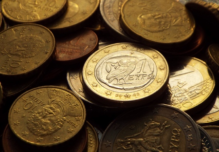 Greek euro in the dark -  The Greek 1 euro coin is lying on a pile of coins.の写真素材