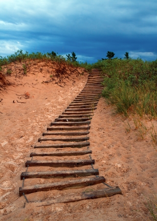 A trail of timber steps lead up a dune and toward a dark evening sky at Michiganの写真素材