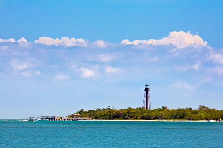 People on a pier, boats, and a sandy beach are backed by the brown metal tower of Floridaの写真素材