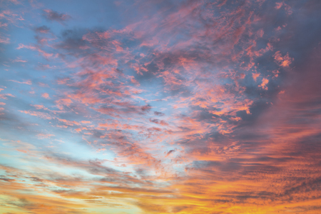 Gossamer clouds glow pink in a colorful sunrise sky.の写真素材