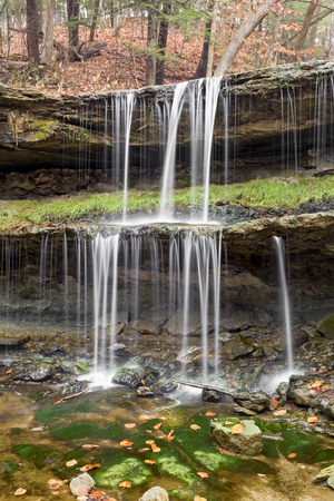 Water splashes down the two tiers of the waterfall at Oglebay Park in Wheeling, West Virginia with autumn leaves here and there.の写真素材