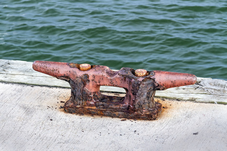 An old dock cleat rusts at the water's edge.の写真素材