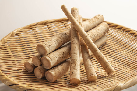 Burdock roots in a wicker basket on a white backgroundの写真素材