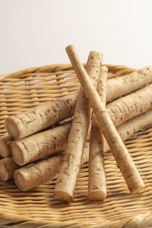 Burdock root in a wicker basket on a white backgroundの写真素材