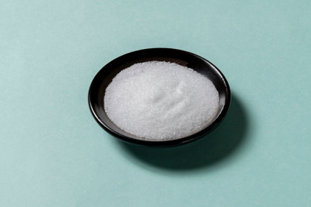 sugar in a bowl on a turquoise background, top view