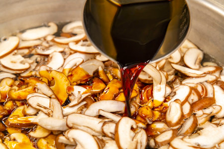 Pouring red wine into a pan with champignon mushrooms.の写真素材