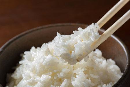 Japanese rice in a bowl with chopsticks on a wooden background.の写真素材